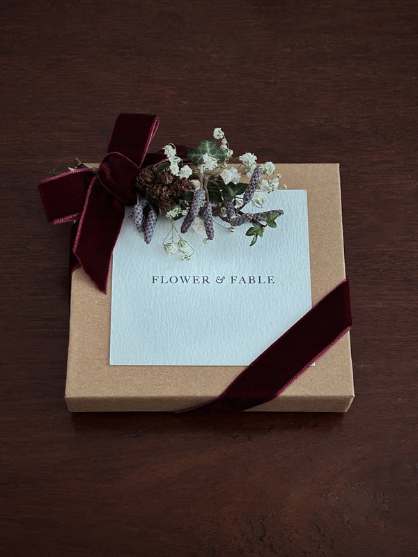 Gift box with a card and flower posy on a wooden surface