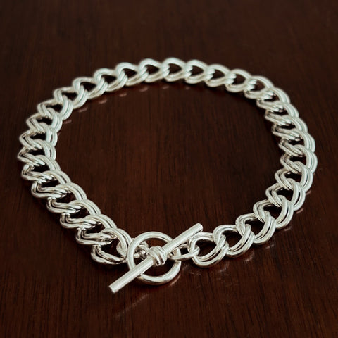 Sterling Silver double curb chain bracelet with a t bar clasp on a wooden surface