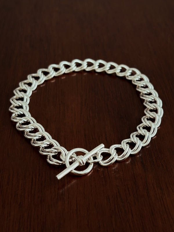 Sterling Silver double curb chain bracelet with a t bar clasp on a wooden surface