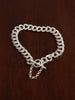 Silver bracelet chain with a t bar closure and safety chain on a wooden surface