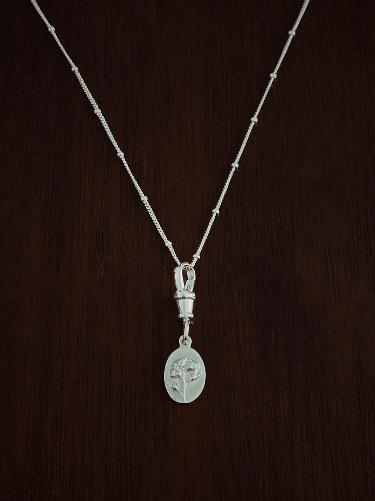 Silver necklace with a pendant and albert swivel clasp on a dark wooden background