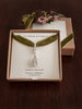 Silver forget-me-not medal charm and albert swivel clasp displayed on velvet ribbon in a 'Flower & Fable' box with decorative elements on a wooden surface