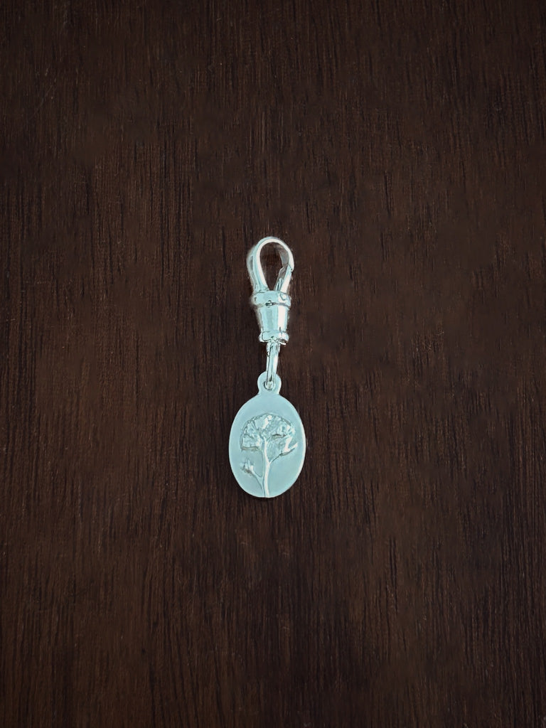 Silver forget me not medal close up with an albert swivel clasp on a wooden surface