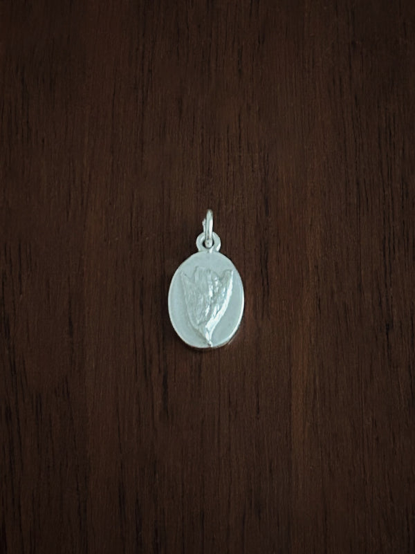 Silver gorse flower pendant on a wooden surface