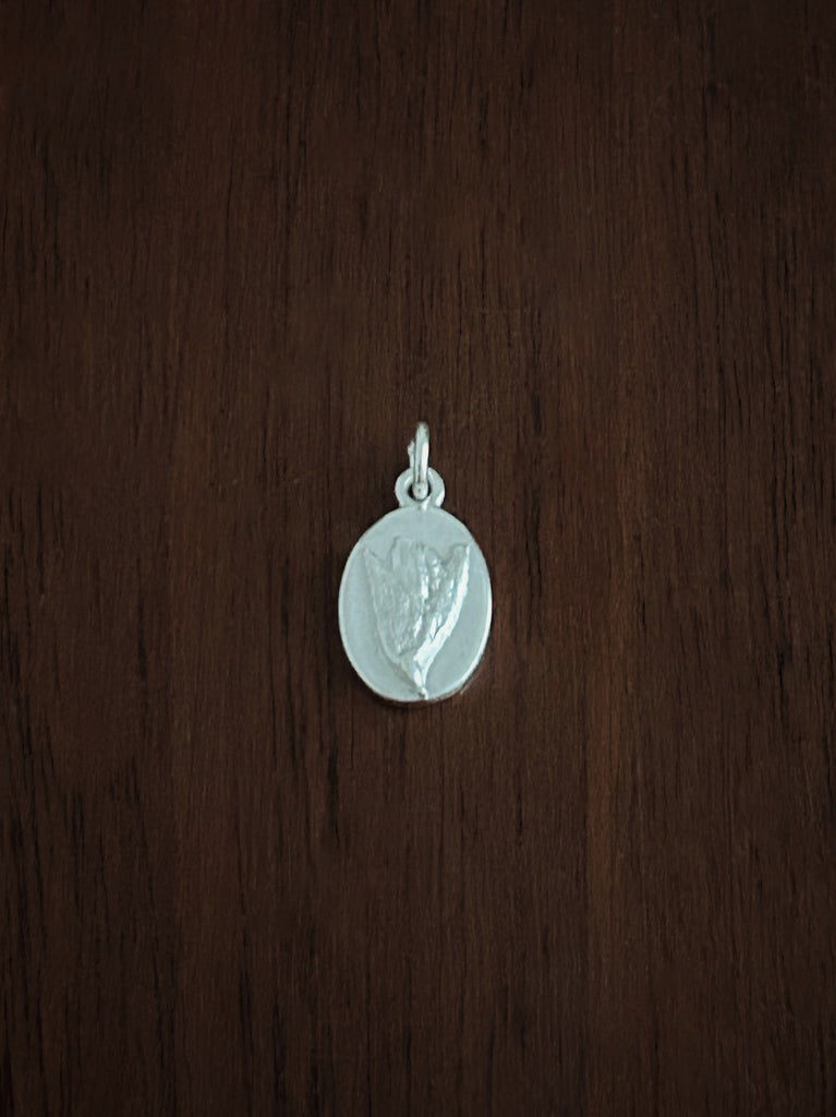 Silver gorse flower pendant on a wooden surface