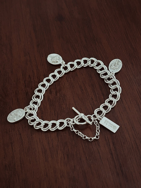 Silver chain bracelet with charms on a wooden surface