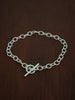 Heavy trace Silver chain bracelet with a t bar closure on a wooden surface