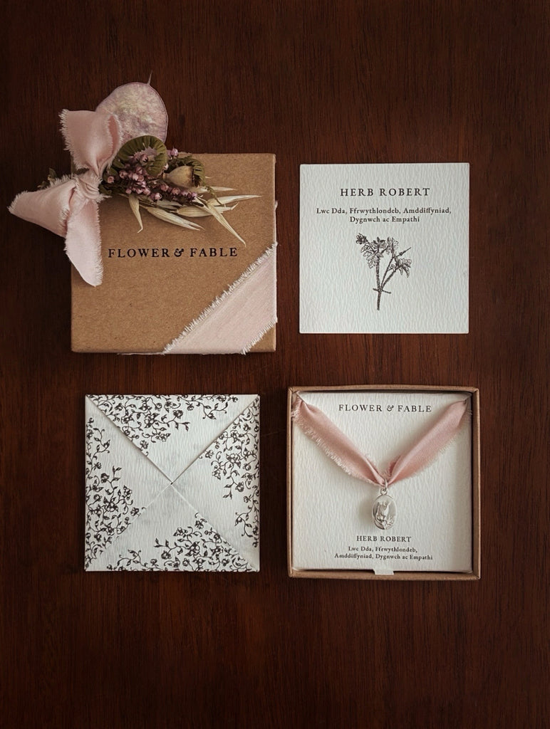 Sterling Silver pendant with Flower & Fable packaging in Welsh on a wooden surface