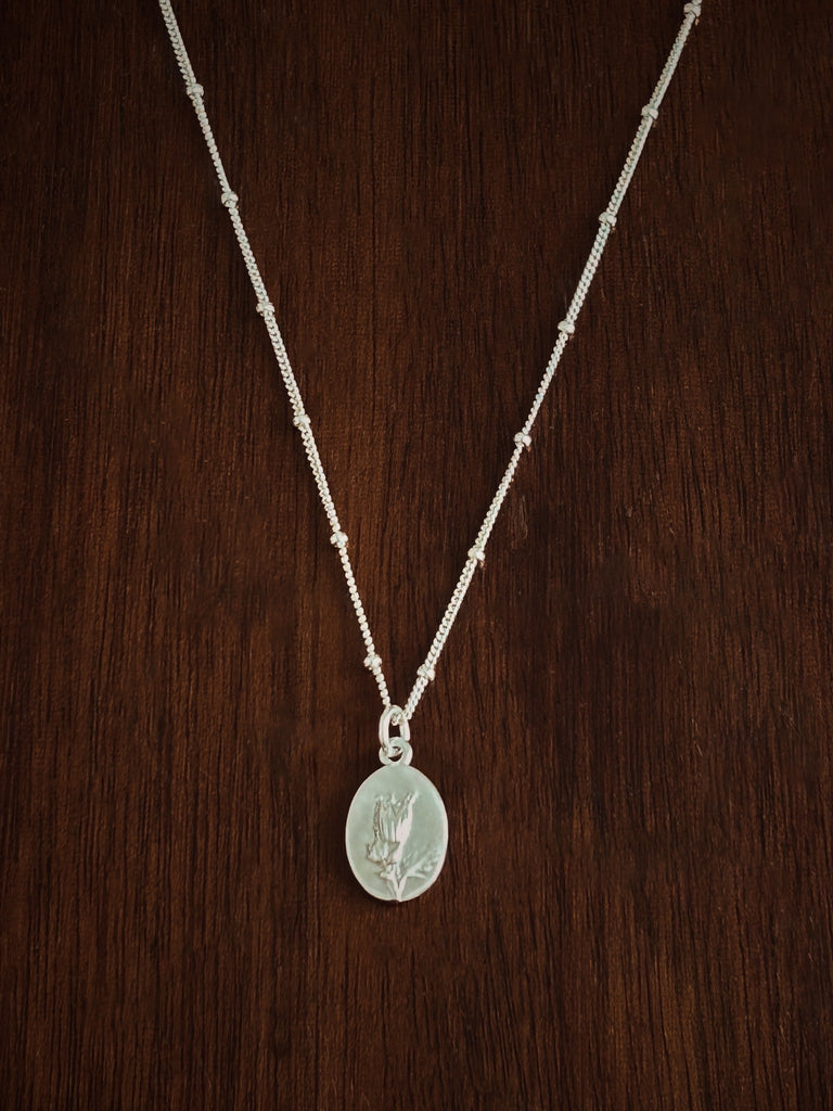 sterling Silver necklace with a flower pendant on a wooden surface