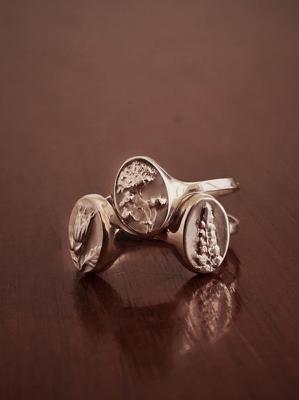 Sterling Silver adjustable Signet Rings. 3 different flowers on a drk wood background