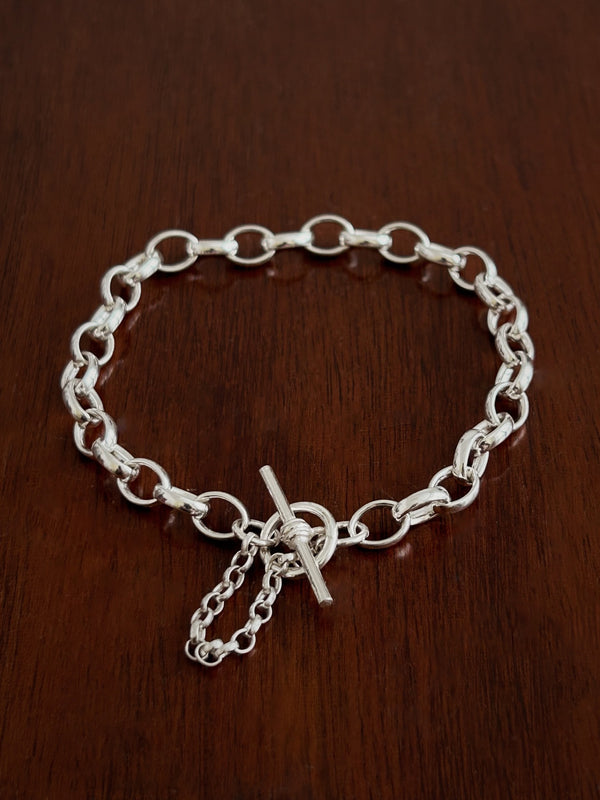 Silver belcher chain t bar bracelet with a safety chain on a wooden surface
