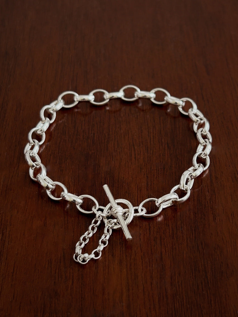 Silver belcher chain t bar bracelet with a safety chain on a wooden surface