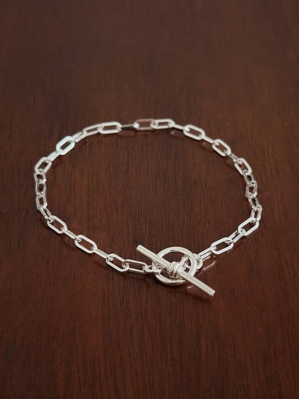 Sterling Silver paperclip chain bracelet with a b bar closure on a wooden surface