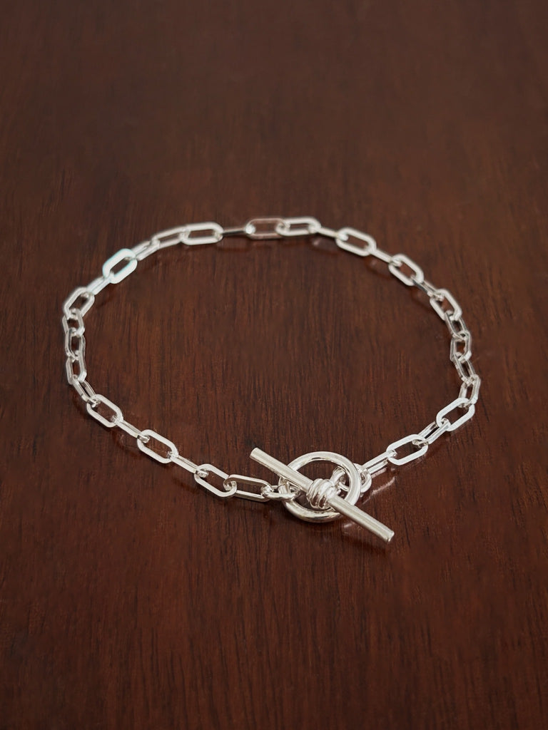 Sterling Silver paperclip chain bracelet with a b bar closure on a wooden surface