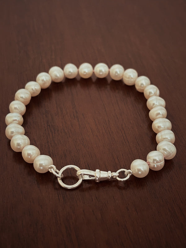 Pearl bracelet with a silver clasp on a wooden surface