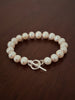 Pearl bracelet with a silver t-bar closure on a wooden surface