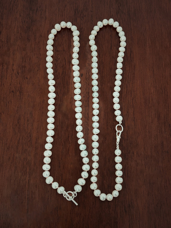 Pearl necklace showing both fastinings on a wooden surface