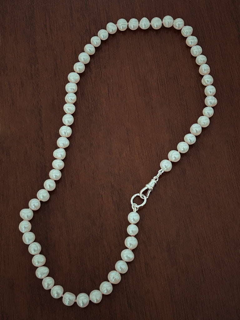 Sterling silver Albert clasp fastening on hand-knotted pearl necklace, designed for attaching charms or linking multiple strands.