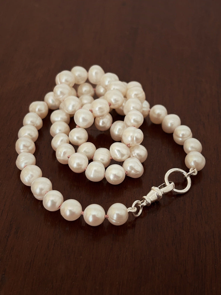 Close-up of cultured freshwater pearls hand-knotted on silk thread, showing soft lustre and traditional knotting technique.