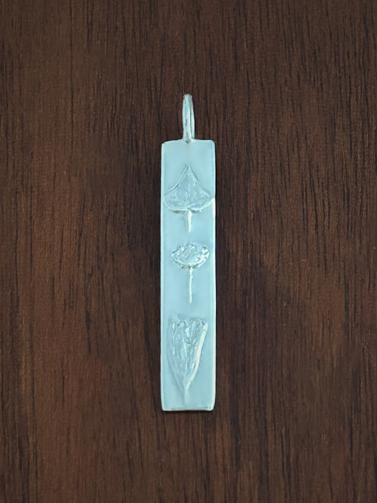 Silver sisterhood pendant on a wooden surface