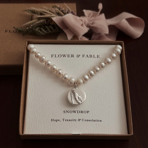 Pearl necklace with a silver snowdrop 
pendant in a 'Flower & Fable' box on a dark background