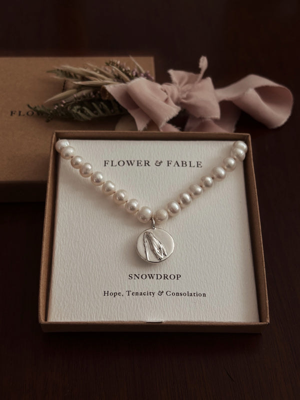 Pearl necklace with a silver snowdrop 
pendant in a 'Flower & Fable' box on a dark background
