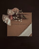Floral arrangement and bow on a brown card with 'FLOWER & FABLE' branding against a dark background