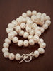 Classic pearl necklace worn at choker length, showing natural sheen and delicate silk knotting.