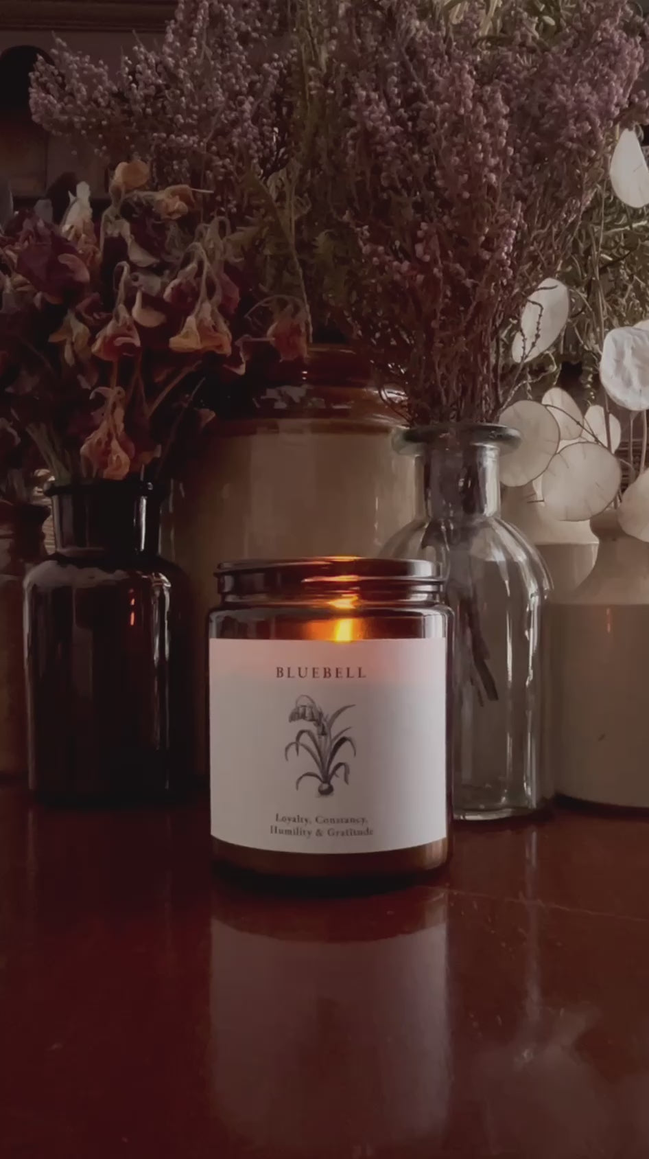Video of a hand poured soy candle in amber glass with a crackling wood wick
