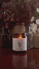 Video of a hand poured soy candle in amber glass with a crackling wood wick